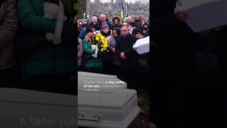 A father gently rocks the small coffin of his one-year-old son.